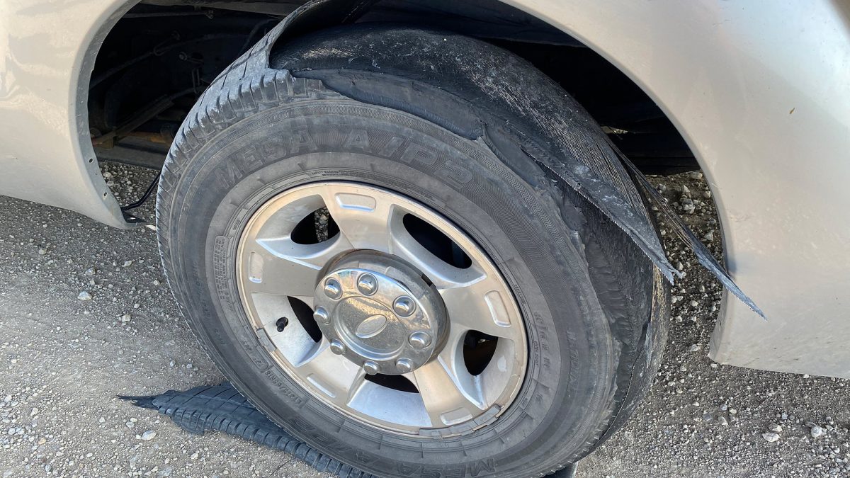 A tire with treads ripped and flapping while towing a camper on a Kansas back road.