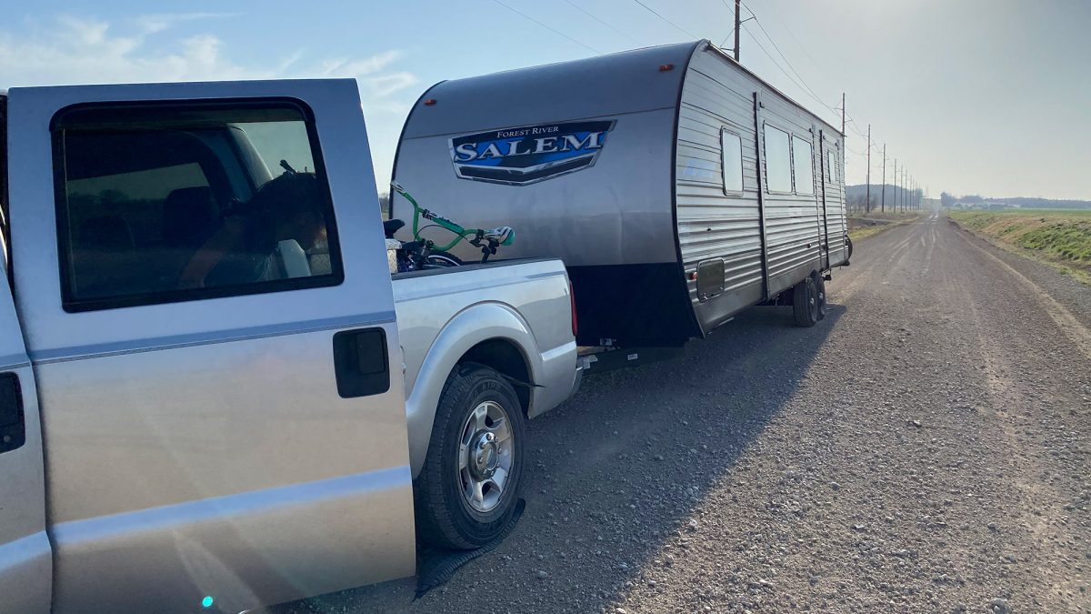 A shredded tire on a truck towing a camper.